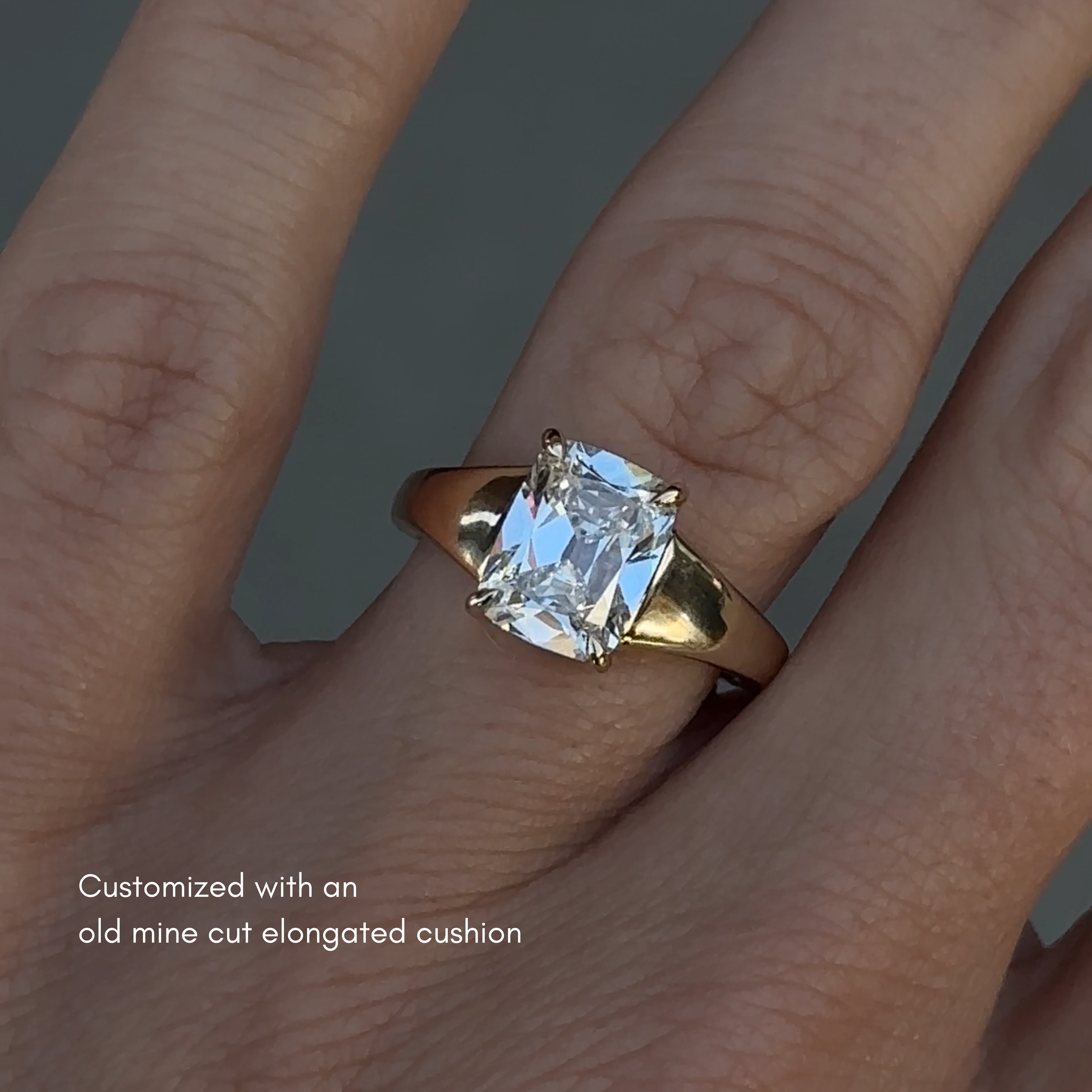 Chunky engagement ring that tapers from the center stone to the back of the ring. The ring is on the hand. The center stone is an old mine cut elongated cushion that is 2.5ct. 