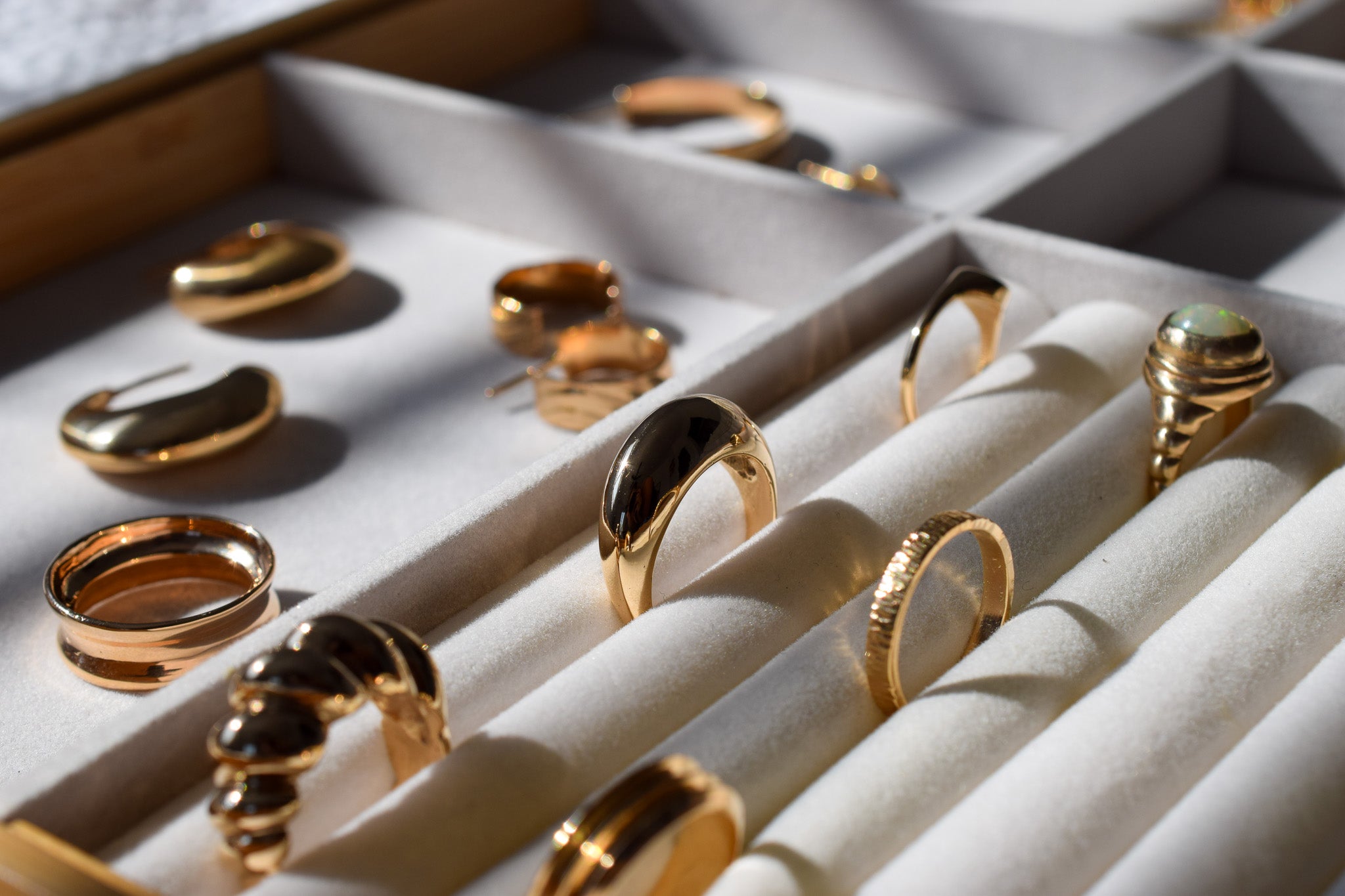 A jewelry tray with white interior that is holding 14k yellow gold rings in varying styles.